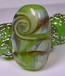 I swirled some silver glass with Jelly Bean and encased it and it held it's color and allowed the silver glass to create some beautiful color and mother of pearl reactions. Very difficult to photograph it's glassy goodness.