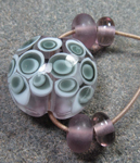 Core of Amethyst encased in clear and then 4 alternating dots of Effetre white and Midnight. All of the spacers are made with CiM Amethyst.
