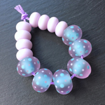 Effetre opaque Light Turquoise 232 encased with Effetre transparent Dark Rossato 083, with spots in Effetre opaque Light Turquoise 232 and CiM Lilac. Spacers are CiM Lilac.
