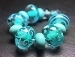 CiM Quetzal encased with Effetre transparent Pale Aquamarine 031, with decoration and spacers in Effetre opaque Light Turquoise 232.