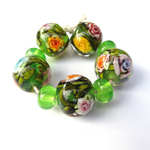 This set of garden beads has a lot of #loriandkim flower murrini on a base of Eclectus Parrot and features leaf cane made with Eden over Effetre Pea Green.